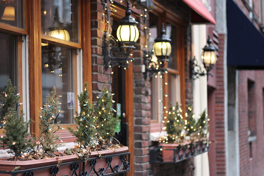 Cozy brick storefront with Christmas lights and small trees