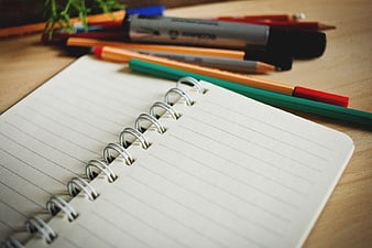 Open Spiral Notebook with Colored Pencils and Markers on Desk