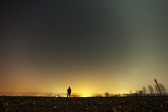 Silhouette of Man Standing in Field Under Starry Night Sky
