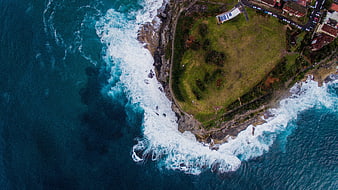 Aerial View of Coastal Cliff with Crashing Waves and Green Park