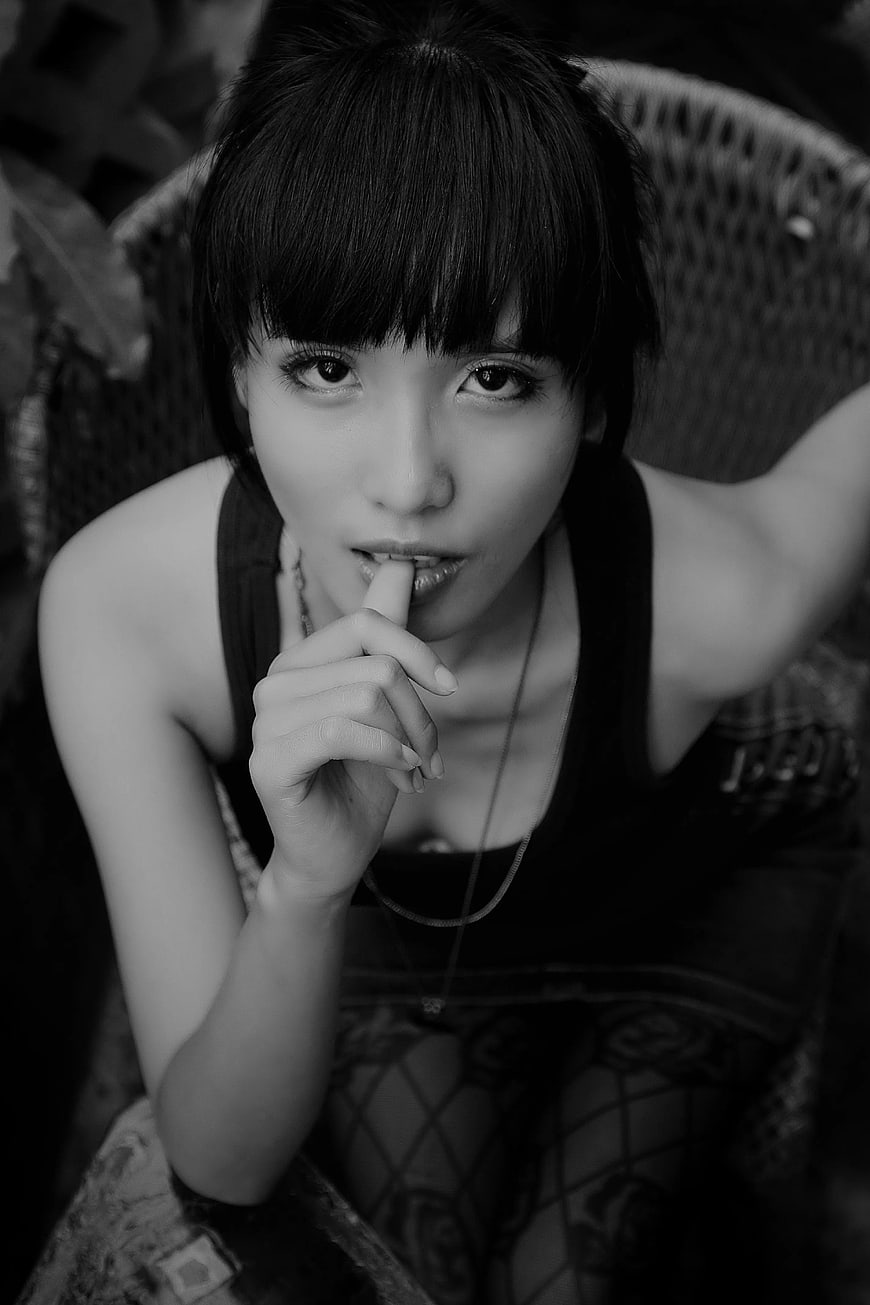 Black and white portrait of woman biting finger