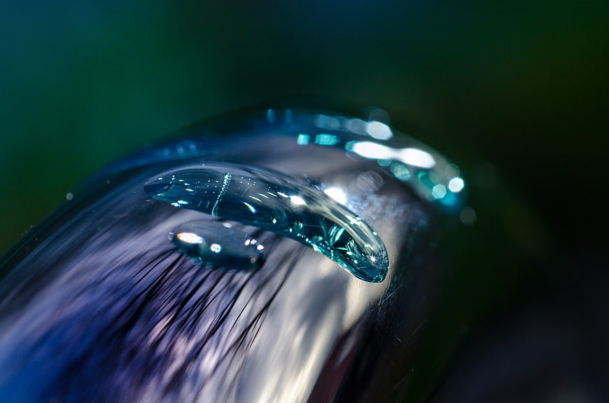 Macro water droplet on metallic faucet surface