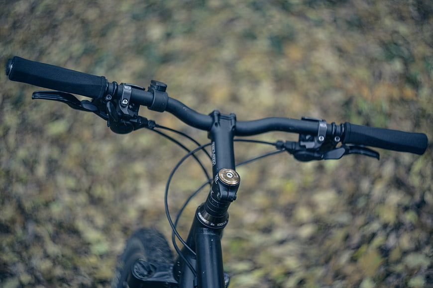 Close-up of black mountain bike handlebars on forest trail