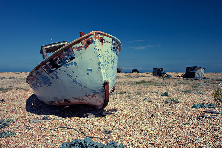 Abandoned weathered boat on pebble beach