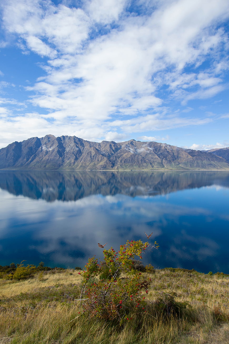 Serene Lake Reflection of Mountains Under Blue Sky