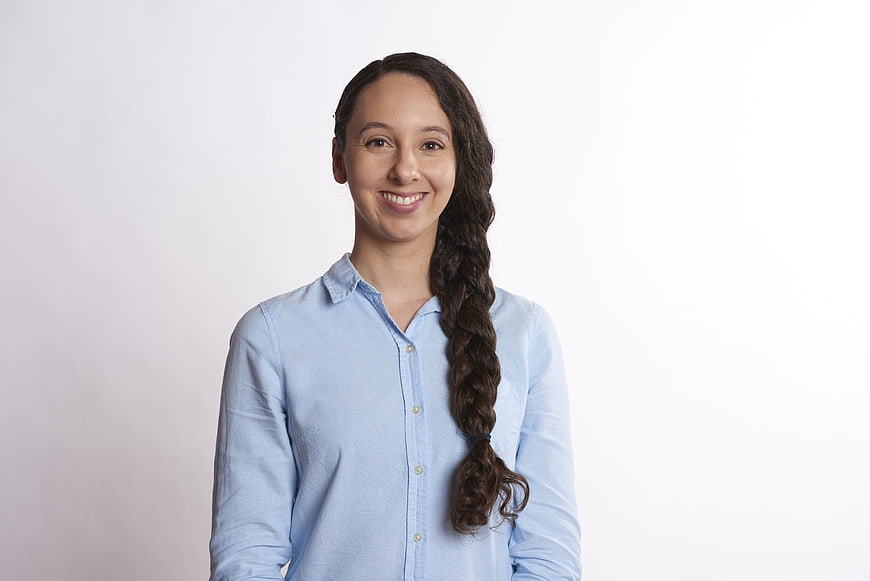 Smiling woman with long braid in blue shirt on white background