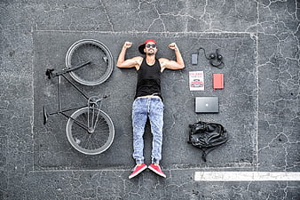 Top View Man Lying on Asphalt with Bike and Laptop