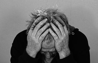 Senior man holding head in hands expressing despair