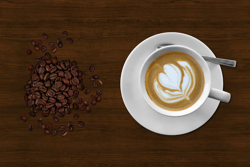 Top View of Latte Art Coffee Cup and Scattered Beans on Wood