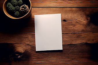 Blank white paper mockup on rustic wooden table with pine cones