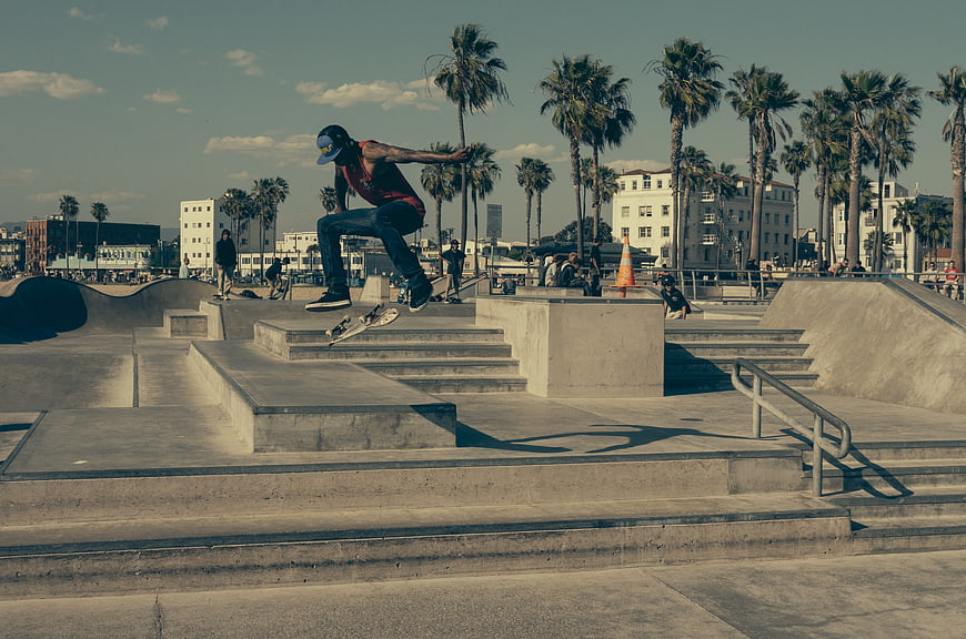 Skateboarder performing kickflip trick at sunny outdoor skate park