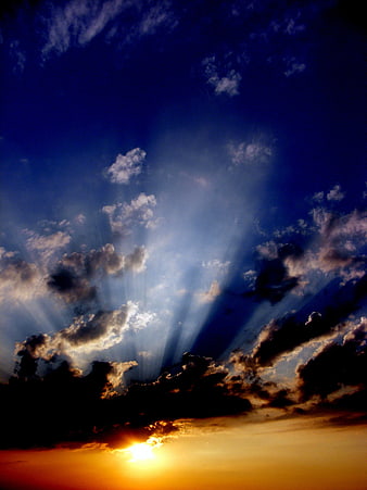 Dramatic sunset with sun rays piercing through dark clouds