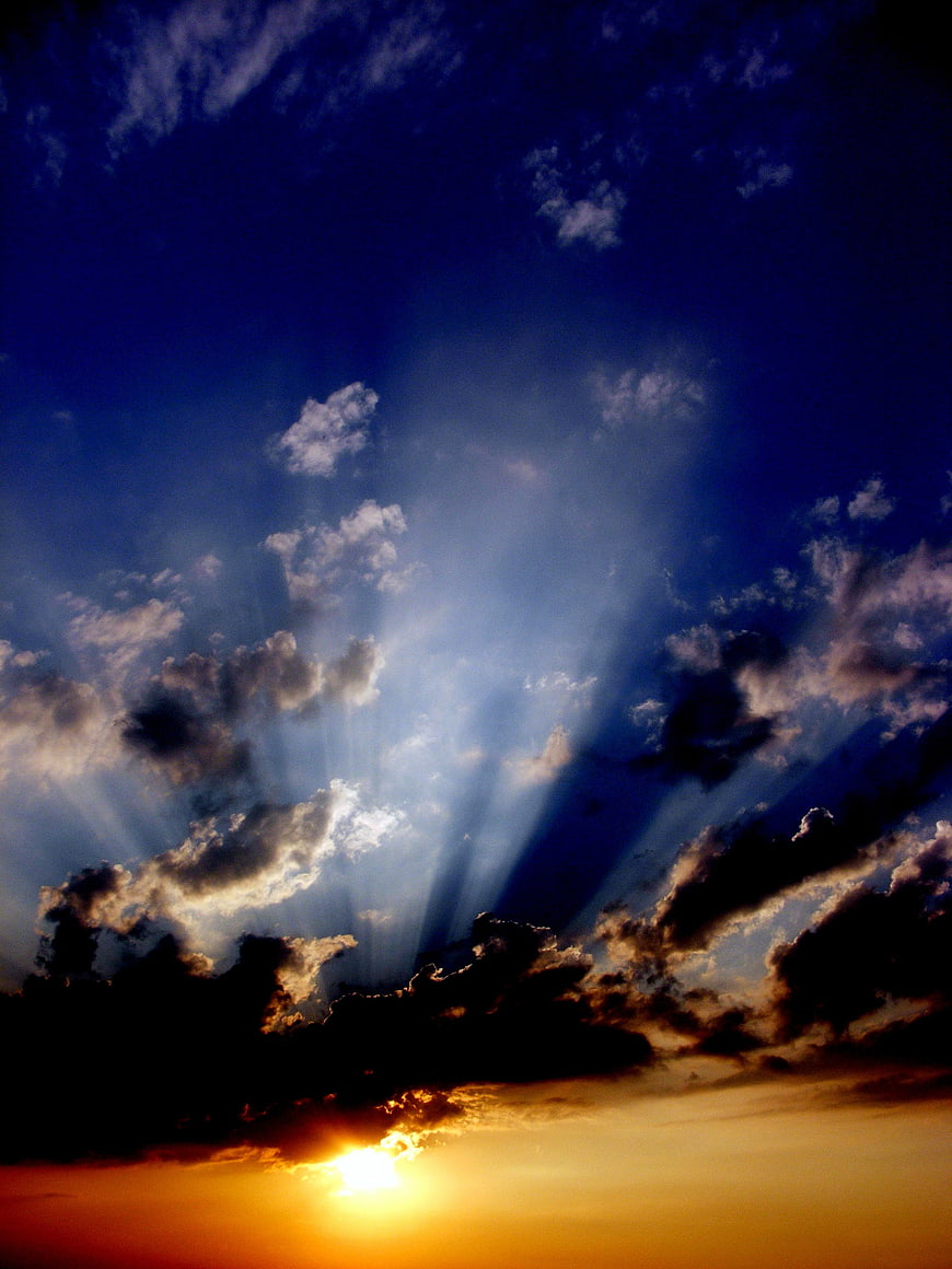 Dramatic sunset with sun rays piercing through dark clouds