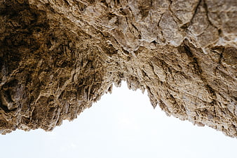 Low angle view of textured rock overhang with sky background