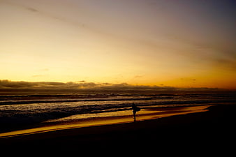 Silhouette of Surfer Walking on Beach at Sunset