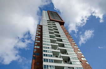 Low angle view of modern Rotterdam skyscraper against blue sky