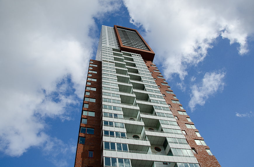 Low angle view of modern Rotterdam skyscraper against blue sky