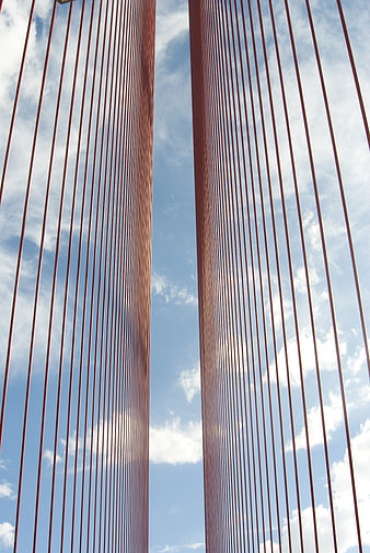 Red suspension bridge cables against blue sky