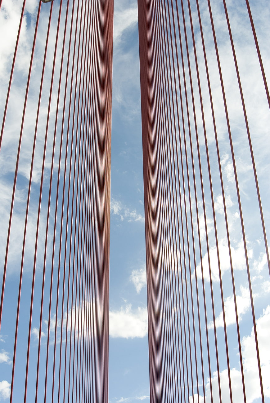 Red suspension bridge cables against blue sky