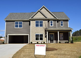 Modern two-story suburban house with under contract sign on front lawn