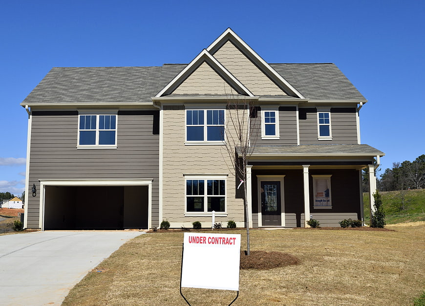 Modern two-story suburban house with under contract sign on front lawn