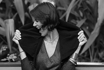 Black and white portrait of a laughing woman holding a dark coat