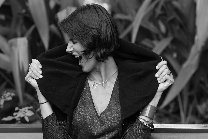 Black and white portrait of a laughing woman holding a dark coat