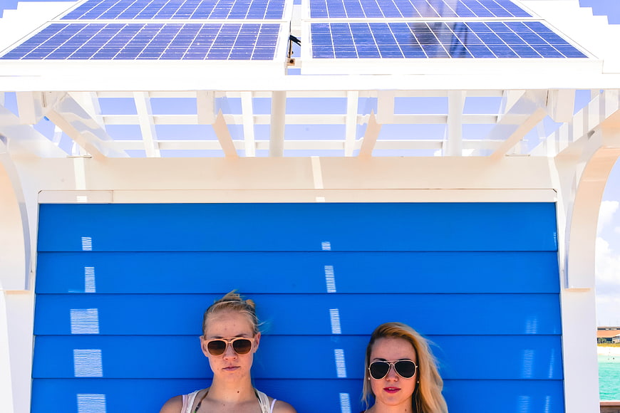 Two women relaxing under solar panels at a beach