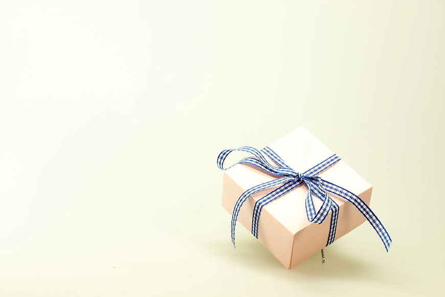 Pink gift box with blue checkered ribbon on cream background