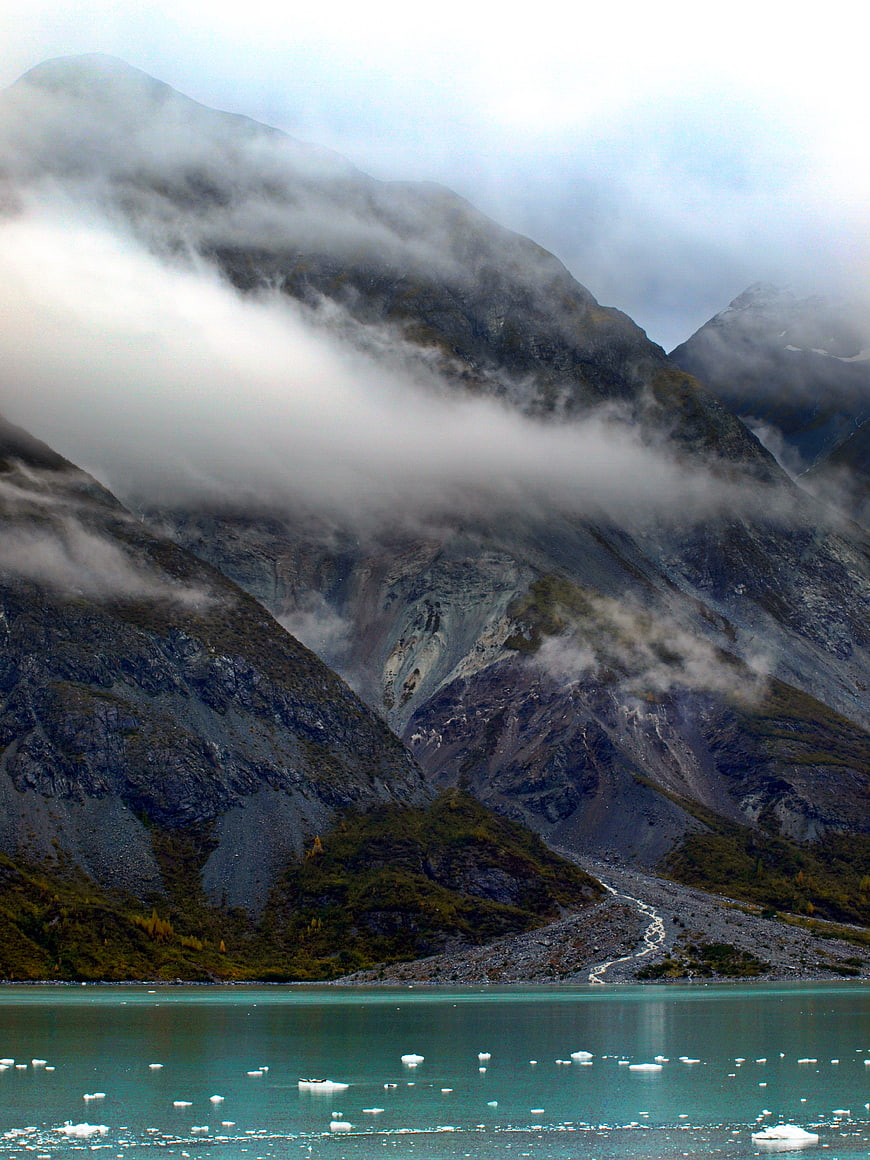 Misty mountain landscape with turquoise glacial lake and floating ice