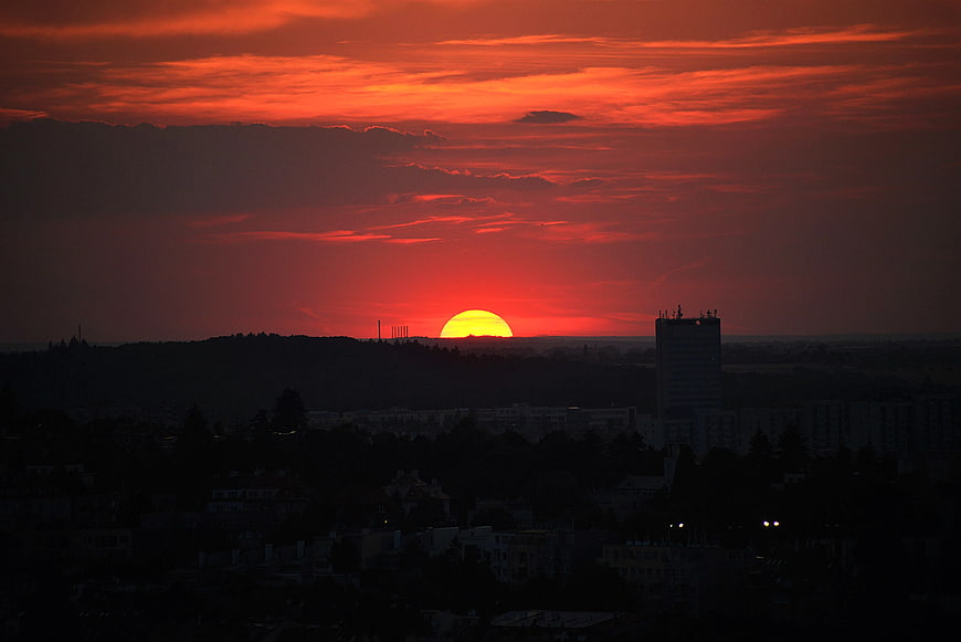 Vibrant Red Sunset Over City Silhouette with Clouds
