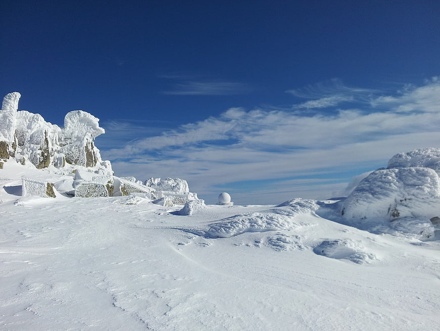 Snow-Covered Mountain Landscape With Deep Blue Sky And Winter Clouds