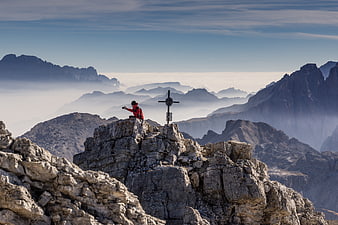 Hiker photographing summit cross above sea of clouds in Swiss Alps