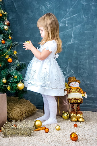 Little girl decorating Christmas tree with gold ornaments