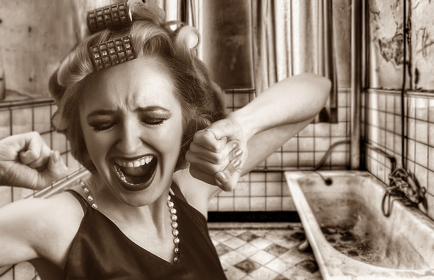 Vintage woman screaming in retro bathroom with hair rollers