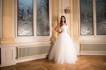 Elegant Bride in White Gown Standing in Ornate Hall