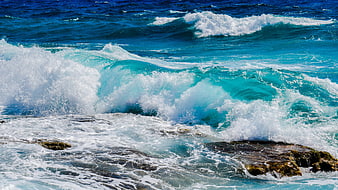 Powerful turquoise ocean waves crashing on rocky shore