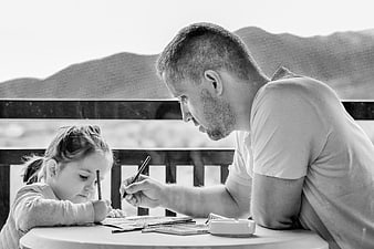 Father and daughter drawing together at outdoor table