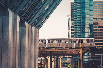 Silver elevated train passing modern glass skyscrapers in city