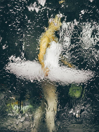 Abstract view of ballerina in yellow tutu through wet glass