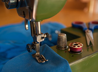 Vintage Sewing Machine Close-Up With Thimble, Scissors, And Blue Fabric