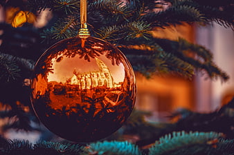 Reflective Christmas Ornament on Pine Branch with Warm Bokeh