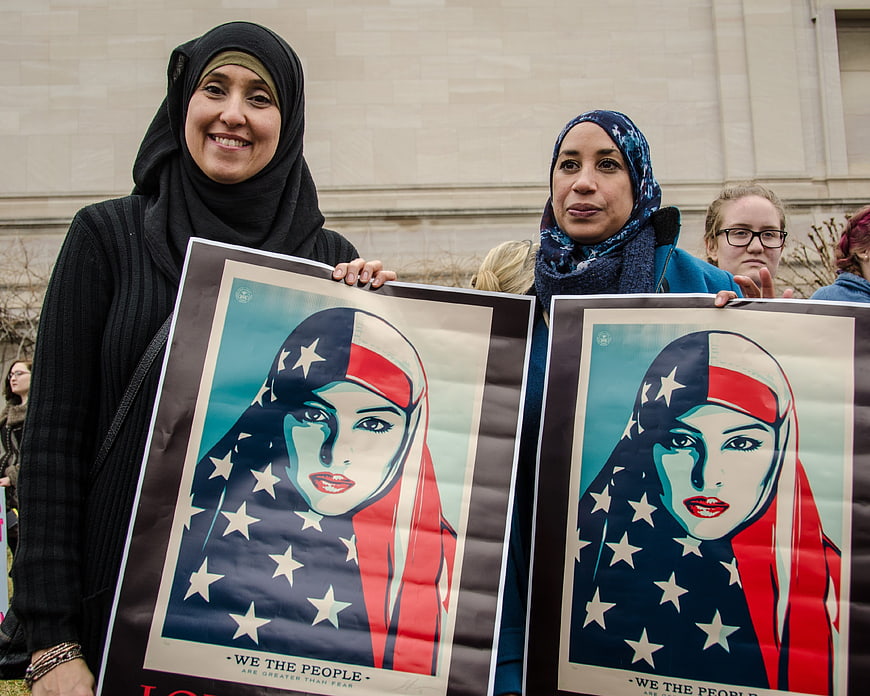 Women holding posters with American flag hijab design at rally
