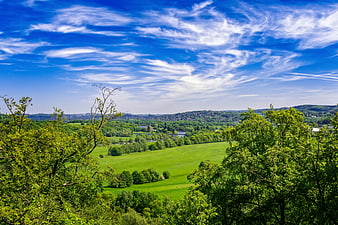 Vibrant Green Countryside Landscape with Blue Sky and Clouds
