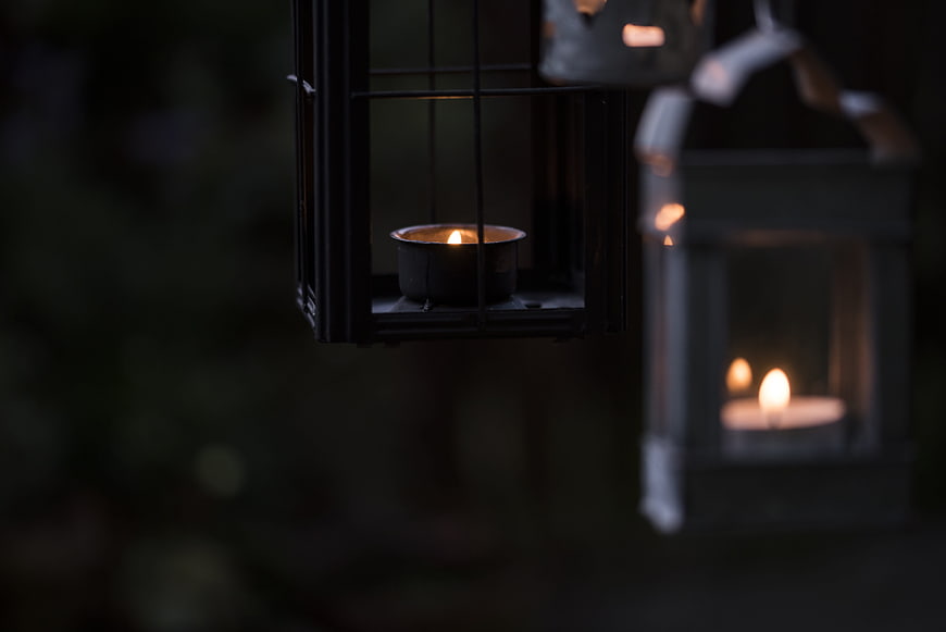 Close-up of lit tea light candles in hanging metal lanterns