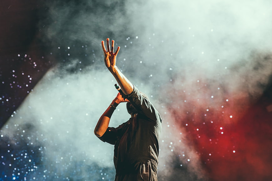 Singer performing on stage with raised hand and microphone