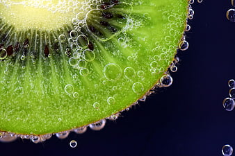 Close-up of fresh kiwi slice submerged in water with bubbles