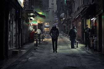Lonely Man Walking Down Snowy City Street at Night