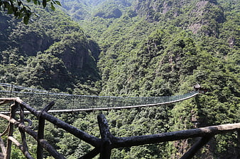 Suspension bridge spanning lush green mountain valley