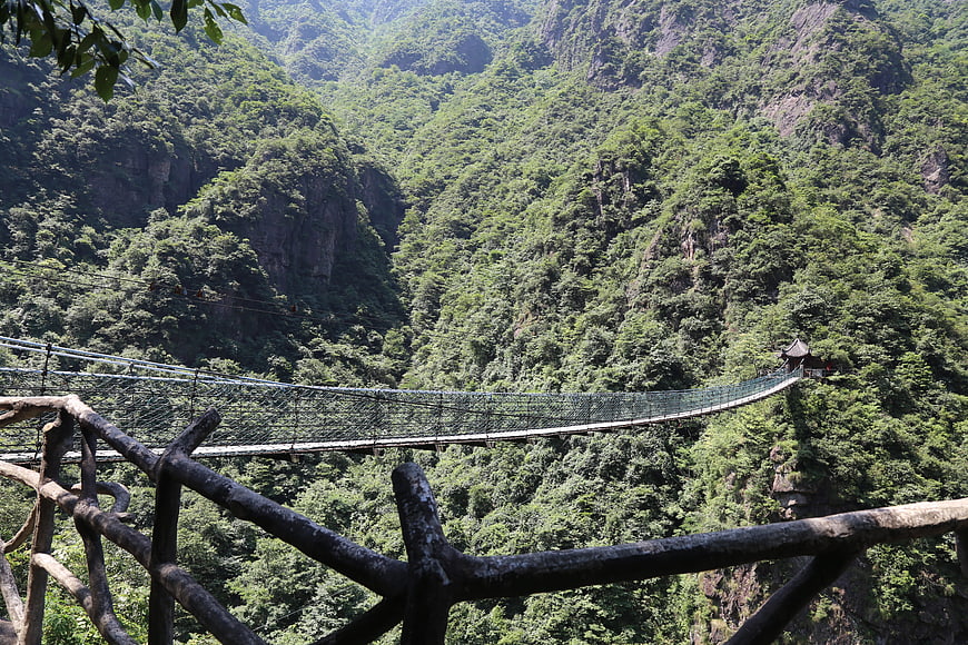 Suspension bridge spanning lush green mountain valley